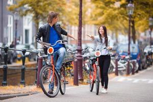 jeune couple caucasien heureux à vélo dans les vieilles rues d'amsterdam photo