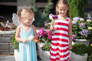 douces petites filles dans une cour de campagne avec des fleurs dans leurs mains photo