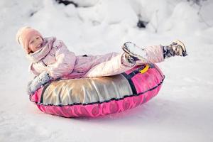 adorable petite fille heureuse faisant de la luge en hiver neigeux. photo