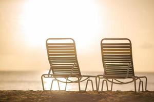 chaises longues blanches sur une belle plage tropicale aux maldives photo