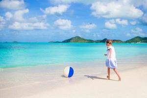adorable petite fille jouant avec un ballon sur la plage. sports d'été pour enfants en plein air sur l'île des caraïbes photo