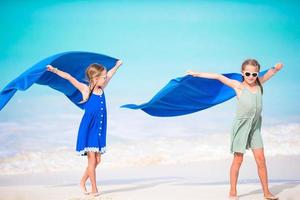 petites filles s'amusant à courir avec une serviette et profitant de vacances sur une plage tropicale avec du sable blanc et de l'eau turquoise de l'océan photo