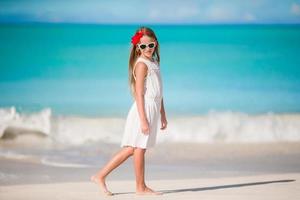 belle petite fille en robe à la plage s'amusant. fille drôle profite des vacances d'été. photo