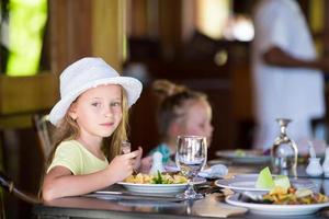 adorable petite fille prenant son petit déjeuner au café en plein air photo