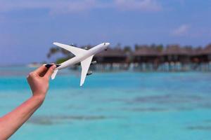 petit avion jouet blanc sur fond de mer turquoise photo