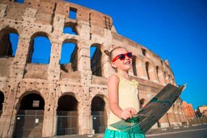 adorable petite fille active avec carte devant le colisée à rome, italie. enfant passant son enfance en europe