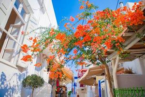 les rues étroites avec des balcons bleus, des escaliers, des maisons blanches et des fleurs dans un beau village en grèce. belle architecture d'extérieur de bâtiment de style cycladique à mykonos