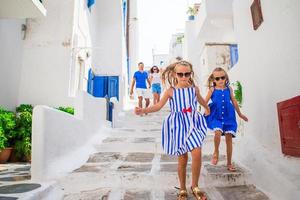 vacances en famille en europe. parents et enfants dans la rue d'un village traditionnel grec typique sur l'île de mykonos, en grèce photo