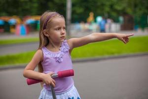 adorable petite fille sur un scooter dans un parc pour enfants photo