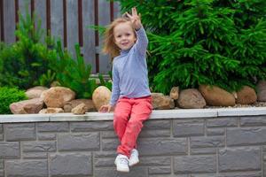 ortrait jolie petite fille près des fleurs dans la cour de sa maison photo