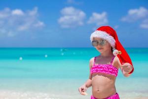 petite fille mignonne en bonnet rouge sur la plage tropicale photo