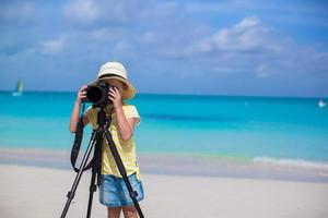 petite fille prenant des photos avec un appareil photo sur un trépied pendant ses vacances d'été