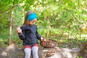 Petite fille cueillant des champignons dans une forêt d'automne photo