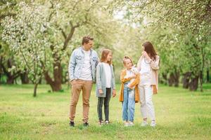 adorable famille dans un jardin de cerisiers en fleurs le beau jour du printemps photo