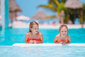 adorables petites filles jouant dans une piscine extérieure en vacances photo