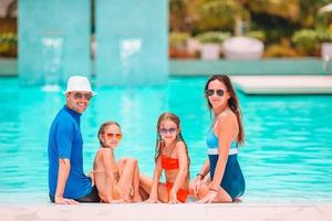 famille heureuse de quatre personnes dans une piscine extérieure photo