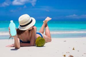 jeune femme souriante appliquant de la crème solaire sur la plage photo