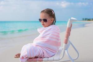 adorable petite fille à lunettes couvertes de serviette à la plage tropicale photo