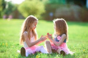 adorables petites filles le jour du printemps à l'extérieur assis sur l'herbe photo