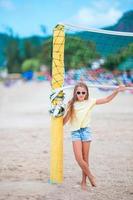 petite fille adorable jouant au beach-volley avec ballon. un enfant sportif profite d'un jeu de plage à l'extérieur photo