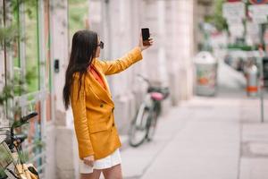 femme parle par son smartphone en ville. jeune touriste attrayant à l'extérieur dans la ville italienne photo
