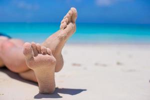 gros plan des jambes des femmes sur la plage de sable blanc photo