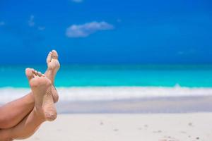 gros plan de pieds féminins sur une plage de sable blanc photo