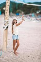 petite fille adorable jouant au volley-ball sur la plage avec ballon. photo