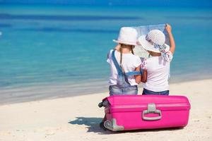 petites filles avec grosse valise et carte à la plage tropicale photo