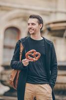 beau jeune homme tenant un bretzel et se relaxant dans le parc photo