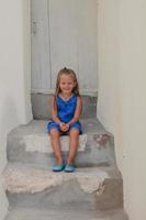 Jolie petite fille assise sur le seuil de la vieille maison du village d'Emporio, Santorin, Grèce photo