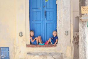 deux petites filles adorables assises sur le seuil d'une vieille maison dans le village d'emporio, santorin, grèce photo