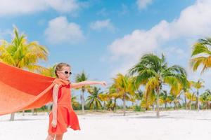 petite fille mignonne jouant au super-héros sur une plage tropicale photo