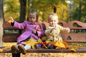 deux petites belles filles assises sur le banc dans une chaude journée d'automne photo