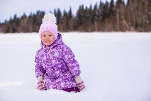 petite fille adorable heureuse s'amusant sur la neige à la journée ensoleillée d'hiver photo