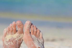 gros plan de pieds féminins sur une plage de sable blanc photo