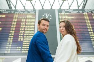 jeune couple à l'aéroport international regardant le panneau d'information de vol photo