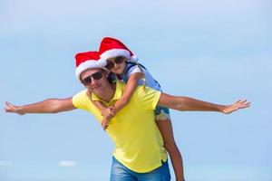 petite fille et papa heureux en bonnet de noel pendant les vacances à la plage photo