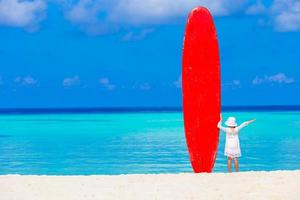 adorable petite fille avec une grande planche de surf pendant des vacances tropicales photo