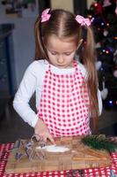 adorable petite fille préparant des biscuits au pain d'épice pour noël photo