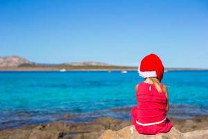 adorable petite fille au chapeau de noël pendant les vacances à la plage photo