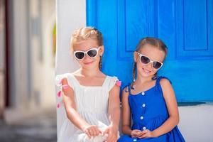 portrait de petites filles souriantes assises près de la vieille porte bleue dans le village grec de mykonos, grec photo