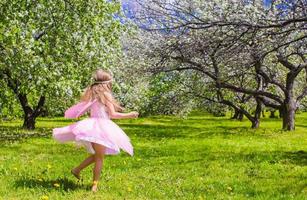 adorable petite fille s'amuse dans un jardin de pommiers en fleurs photo