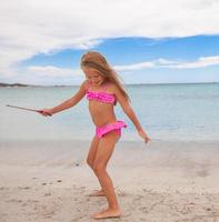 adorable petite fille s'amuser en eau peu profonde à la plage photo