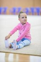 adorable petite fille athlètes s'entraînent dans la salle de gymnastique rythmique photo