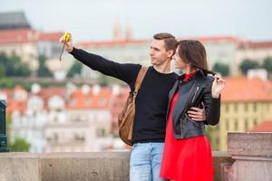 jeune couple voyageant en vacances en europe souriant heureux. famille caucasienne faisant du selfie dans le populaire karlov most photo