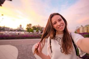 jeune fille faisant selfie et s'amusant dans le parc. portrait de selfie lifestyle de jeune femme positive s'amusant et prenant selfie. concept amusant avec les nouvelles tendances et technologies. photo