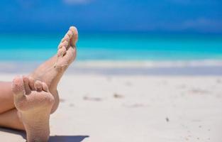 gros plan de pieds féminins sur une plage de sable blanc photo