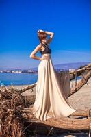 charmante jeune femme en robe longue posant sur la plage photo