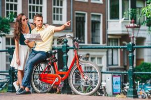 jeune couple caucasien heureux à vélo dans les vieilles rues d'amsterdam photo